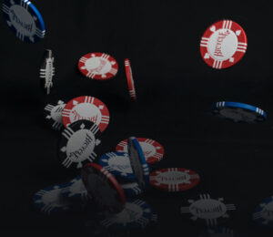 Red and blue poker chips falling to the ground with a pure black background.
