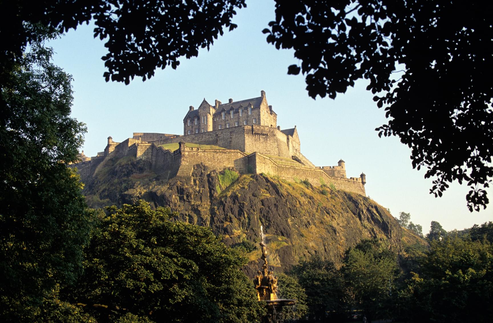 A view through the trees of a Scotland castle on a mountain